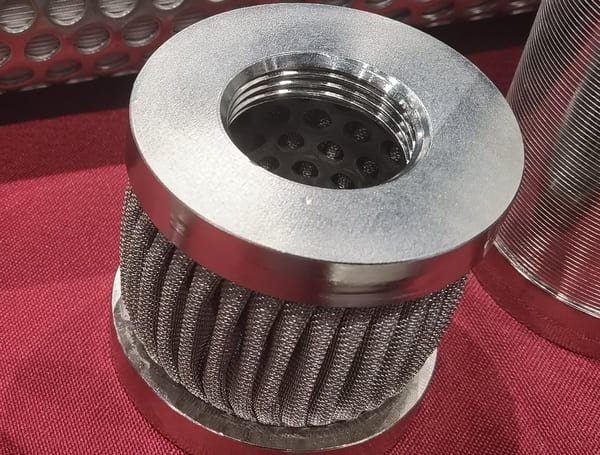 Rolled stainless steel woven wire mesh filter cartridge with a welded seam and welded end caps